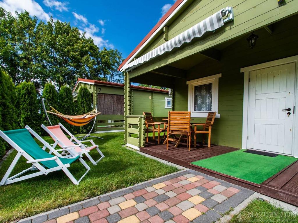 a patio with chairs and a table and a hammock at Domki Romka in Mikołajki