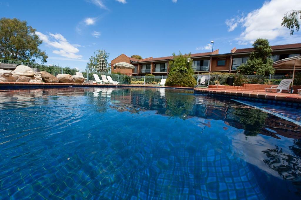 a large swimming pool with blue water in front of a building at Club Mulwala Resort in Mulwala