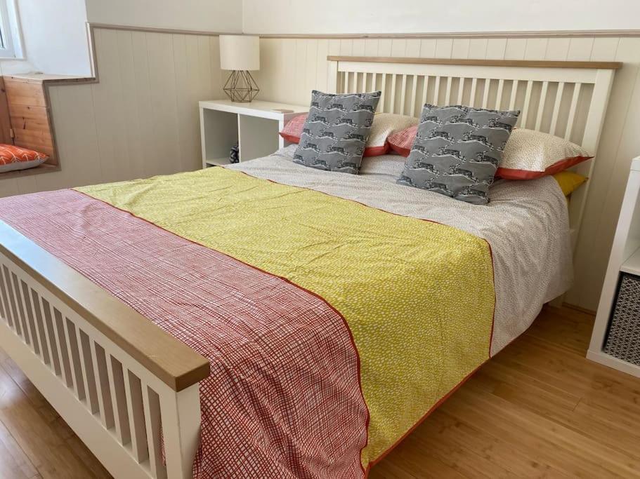 een slaapkamer met een groot bed met een kleurrijke deken en kussens bij The Mexico Inn, Flat One in Ludgvan