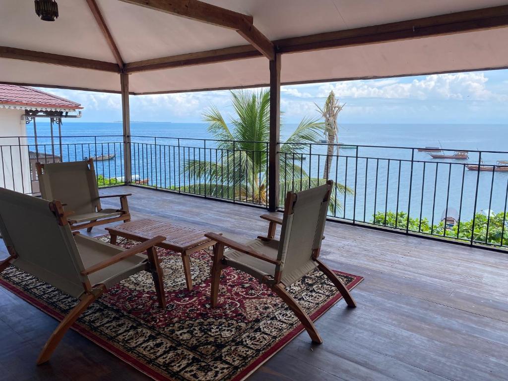 uma varanda com duas cadeiras e uma mesa e o oceano em David Livingstone's Home em Zanzibar