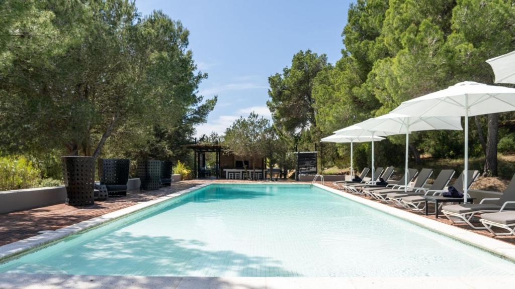a swimming pool with chairs and umbrellas at Magnificent Villa Marama In The Midst Of Ibiza’s Countryside in Sant Jordi