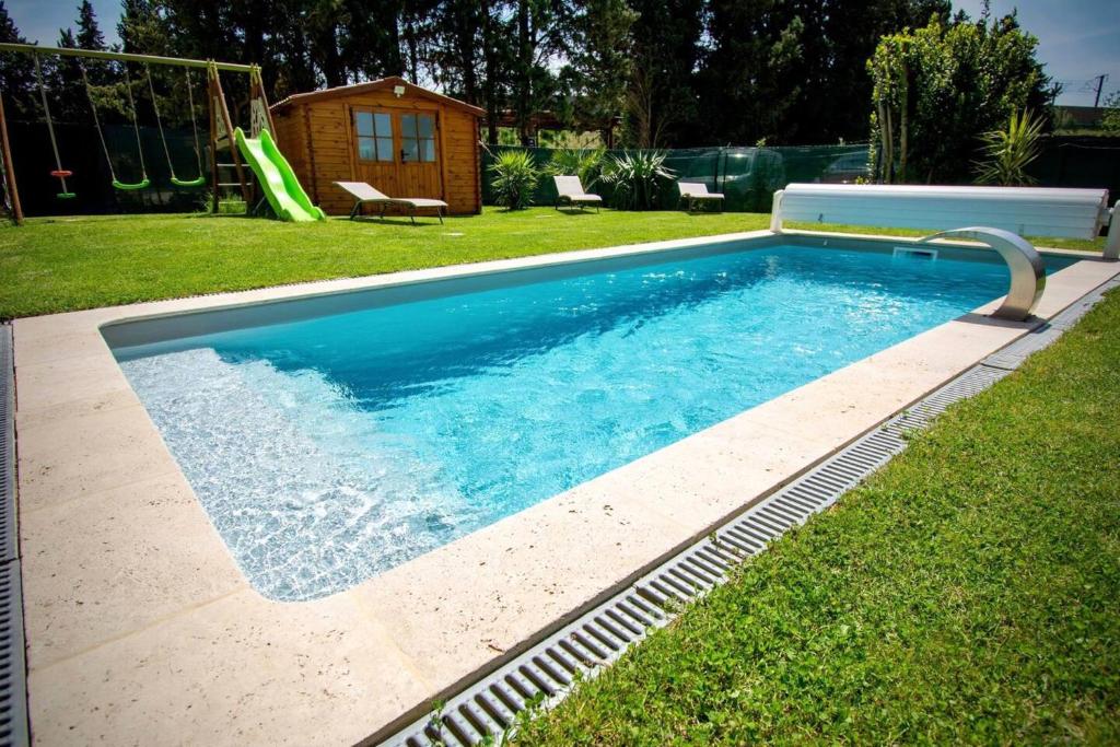 uma piscina num quintal com escorrega em Appartement d'une chambre avec piscine partagee jacuzzi et jardin clos a Avignon em Avignon