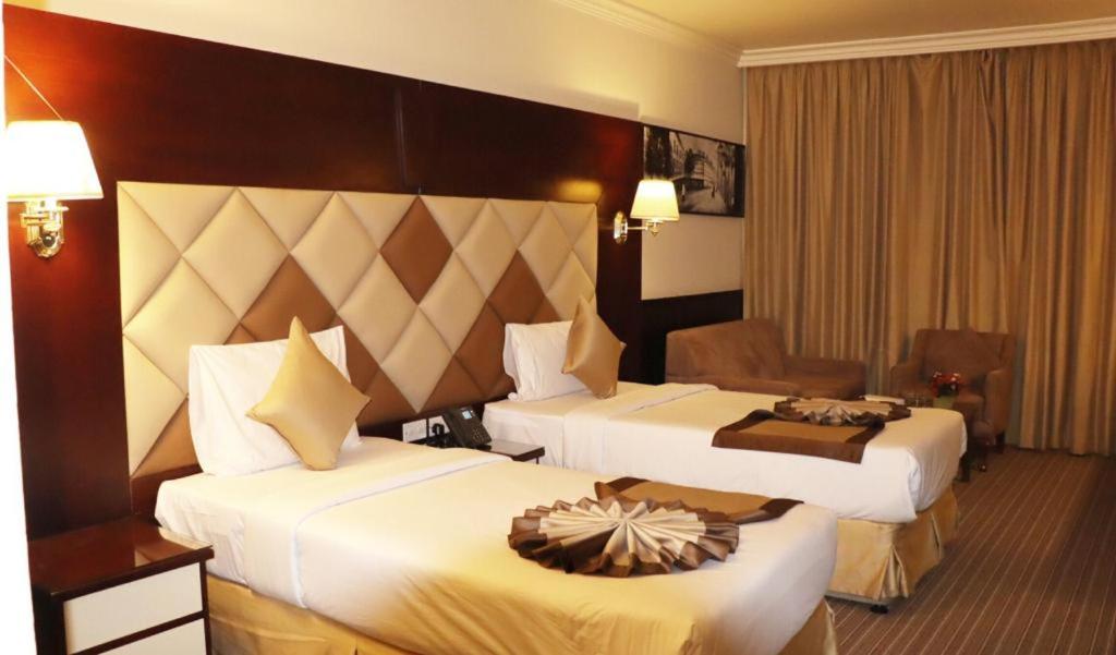 a hotel room with two beds and a chair at Gulf Inn Hotel Deira Formerly City Star Hotel in Dubai