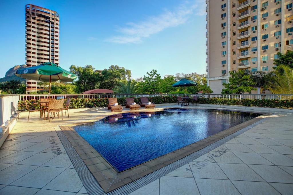 a swimming pool with chairs and umbrellas on a building at Quality Rio de Janeiro - Barra da Tijuca in Rio de Janeiro