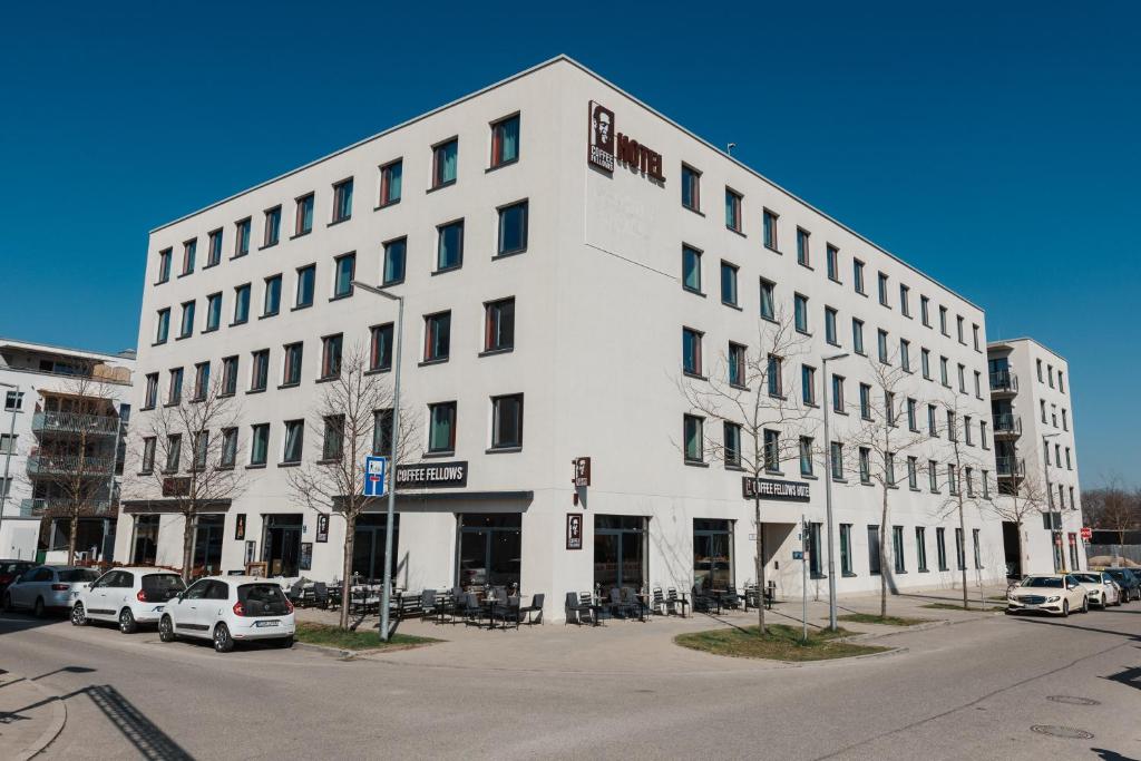 ein weißes Gebäude mit davor geparkt in der Unterkunft Coffee Fellows Hotel München-Freiham in München