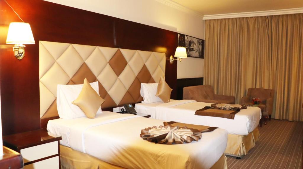 a hotel room with two beds and a chair at Gulf Inn Hotel Deira Formerly City Star Hotel in Dubai