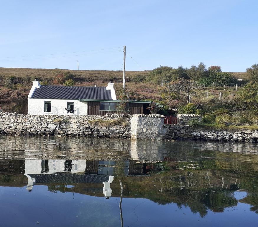 una casa blanca en la orilla de un cuerpo de agua en The Cottar en Broadford