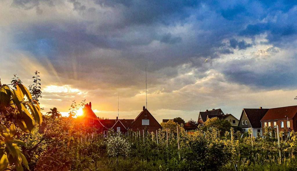 a cloudy sky with the sun setting behind houses at Ferienwohnung Blütenblick in Bachenbrock