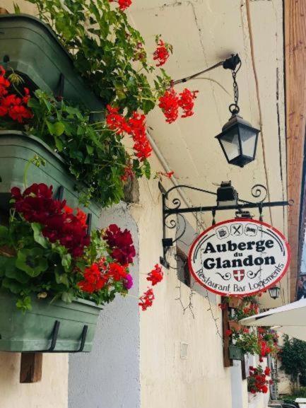 un panneau sur le côté d'un bâtiment avec des fleurs dans l'établissement Auberge du Glandon, à Saint-Colomban-des-Villards