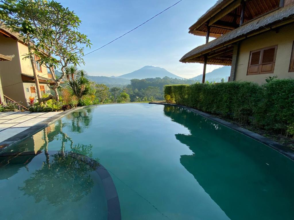 a swimming pool in front of a house with mountains in the background at Kubu Tani in Sidemen
