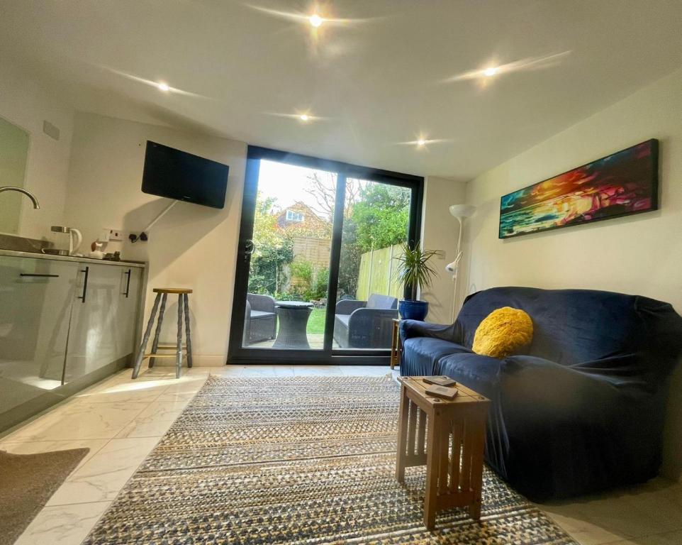 a living room with a blue couch and a kitchen at Sandy Toes in Bournemouth