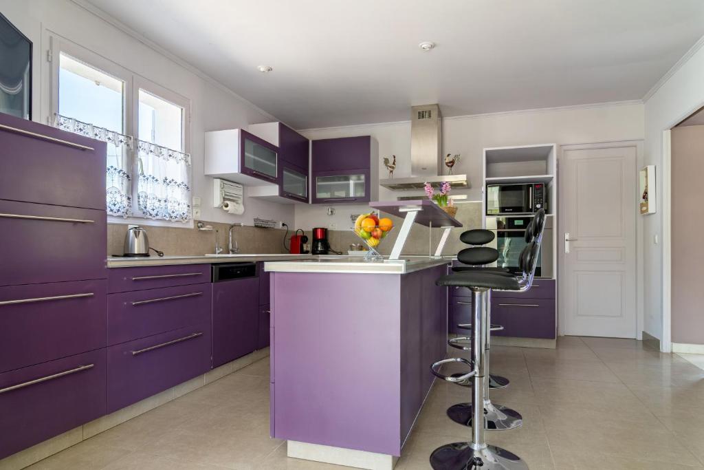 a kitchen with purple cabinets and a bar stool at Les Vergers in Gonfaron
