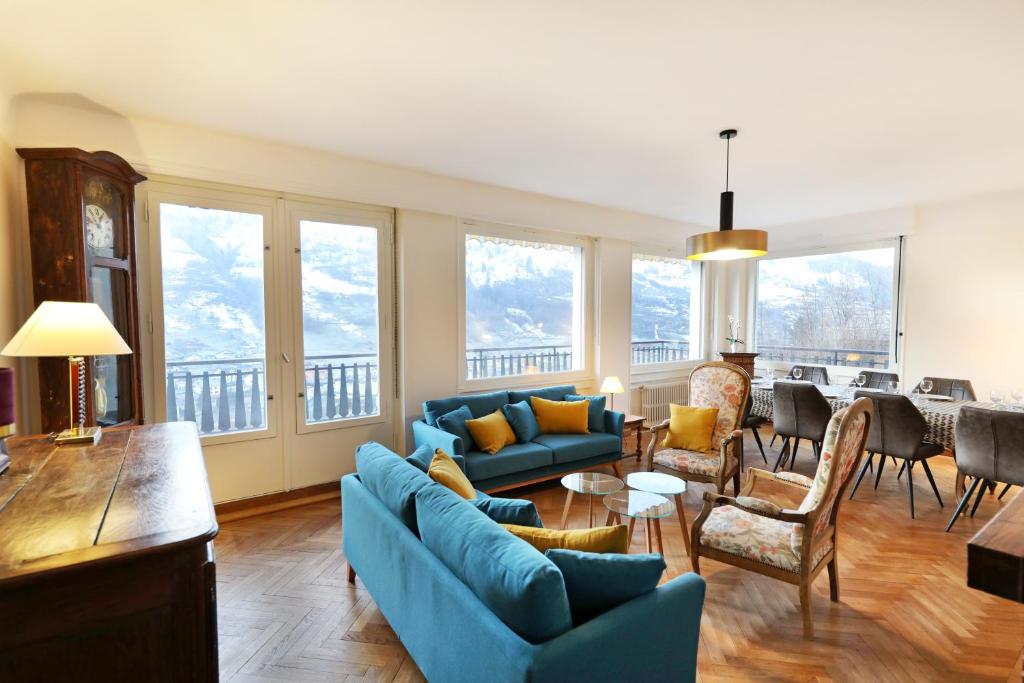 ein Wohnzimmer mit blauen Sofas und ein Esszimmer in der Unterkunft La Maison du Breuil in La Bresse