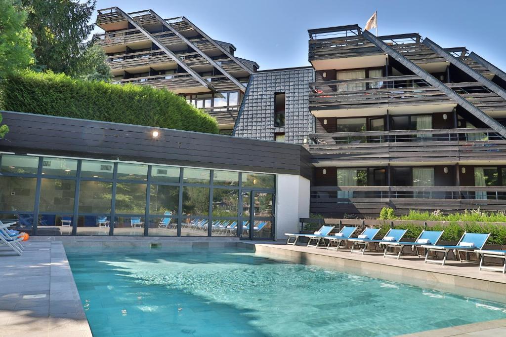een zwembad voor een gebouw met stoelen bij SOWELL HOTELS Mont Blanc et SPA in Saint-Gervais-les-Bains