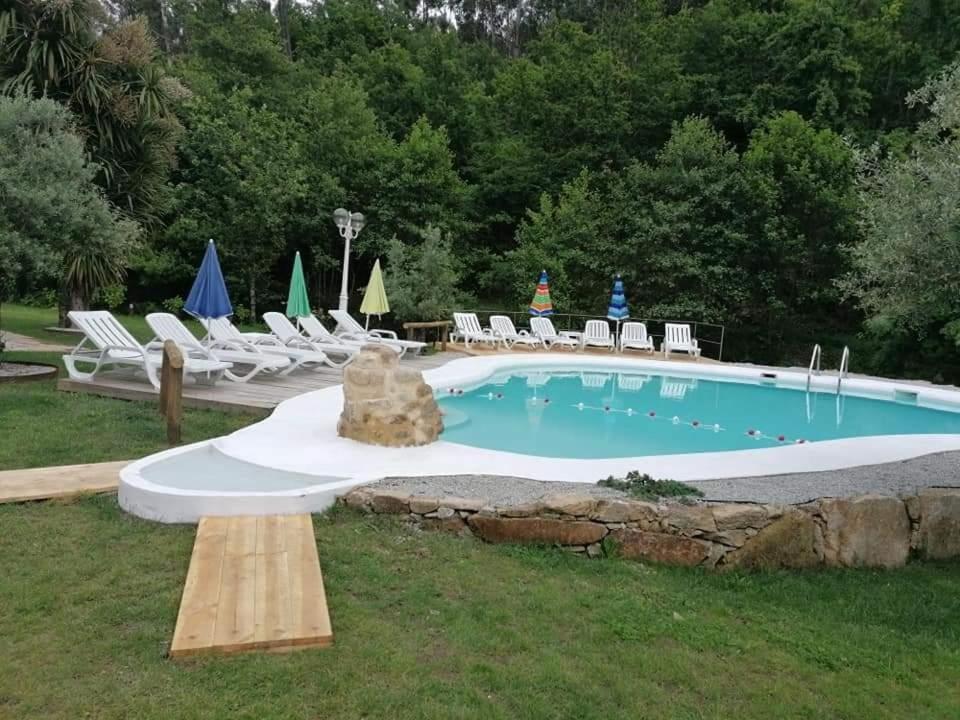 a swimming pool with chairs and a table and a bench at Moinho Azenha do campelo in Vila Verde