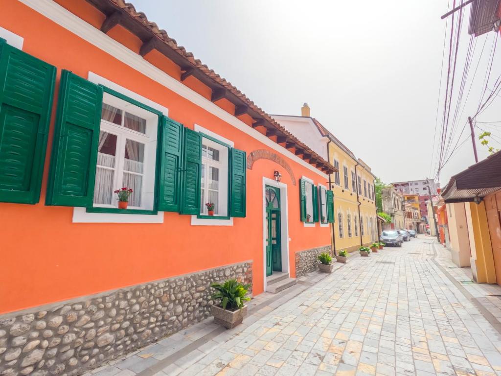 a street with colorful houses and green shutters at InTown Guesthouse Shkoder in Shkodër