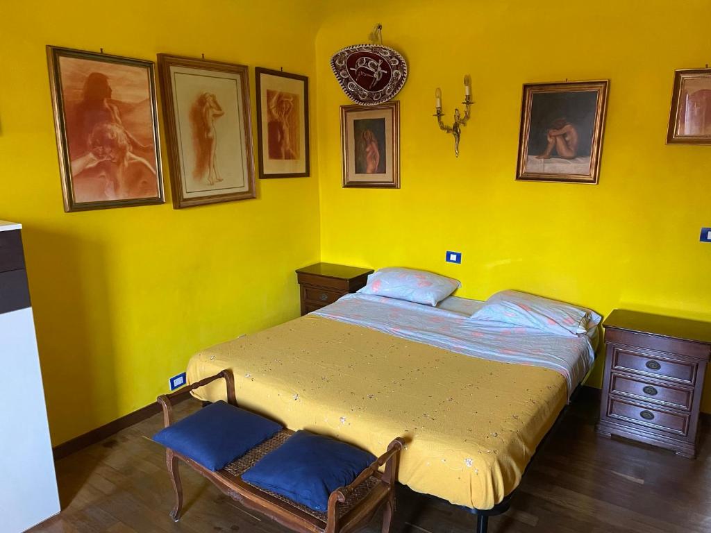 a yellow bedroom with a bed and pictures on the wall at Il Nido del Gabbiano in Savona