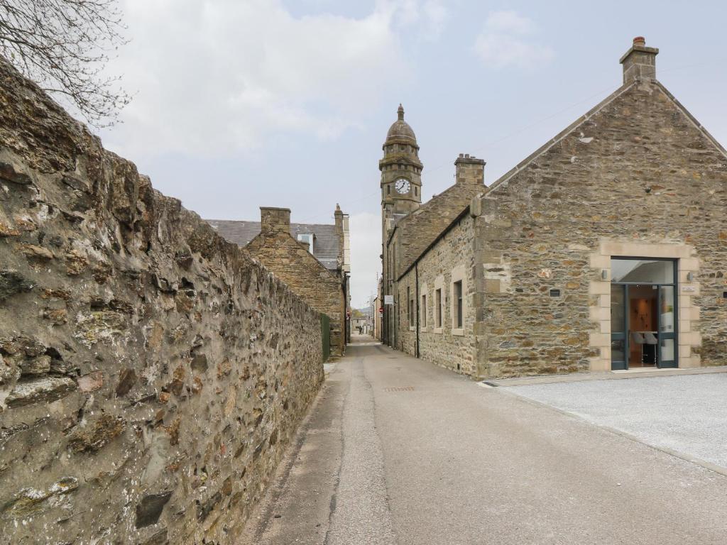 an alley in an old stone building with a clock tower at The Dance Hall at The Institute Executive Apartments in Keith