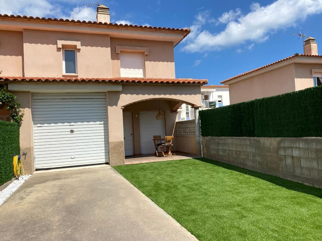 a house with a garage and a green lawn at Casa a L’Escala, piscina comunitaria, Mallols in L'Escala
