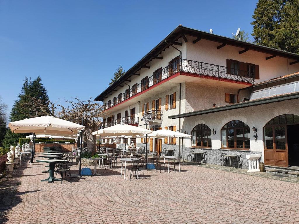 un edificio con tavoli e ombrelloni di fronte ad esso di Hotel Madonna di Luciago ad Armeno