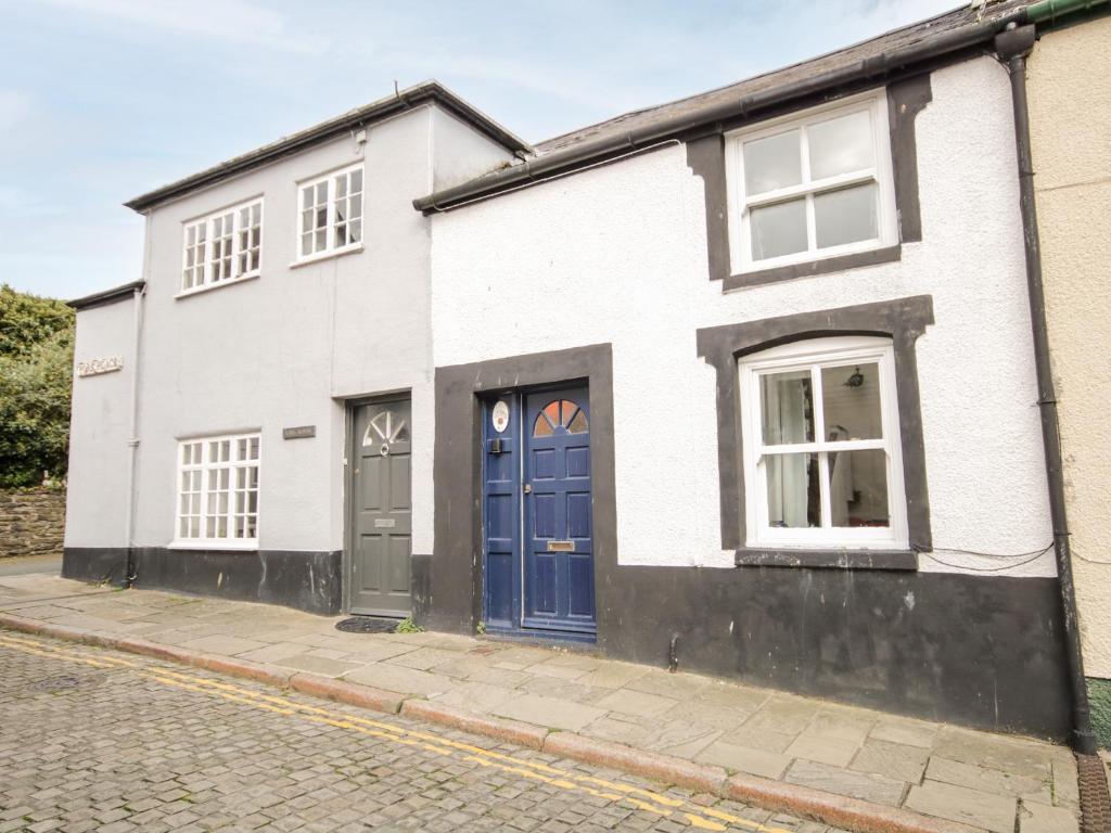 a white house with blue doors on a street at Tudor Cottage in Conwy