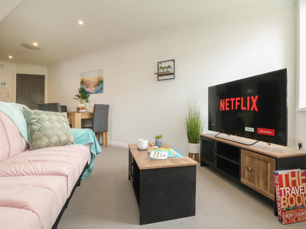 a living room with a couch and a flat screen tv at Lighthouse Lofts - St Anthony in Camborne