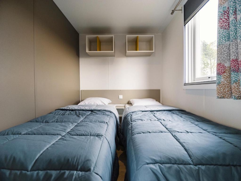 two beds in a small room with a window at Camping Paradis 4 étoiles Au Port de L'Houmeau - La Rochelle in LʼHoumeau