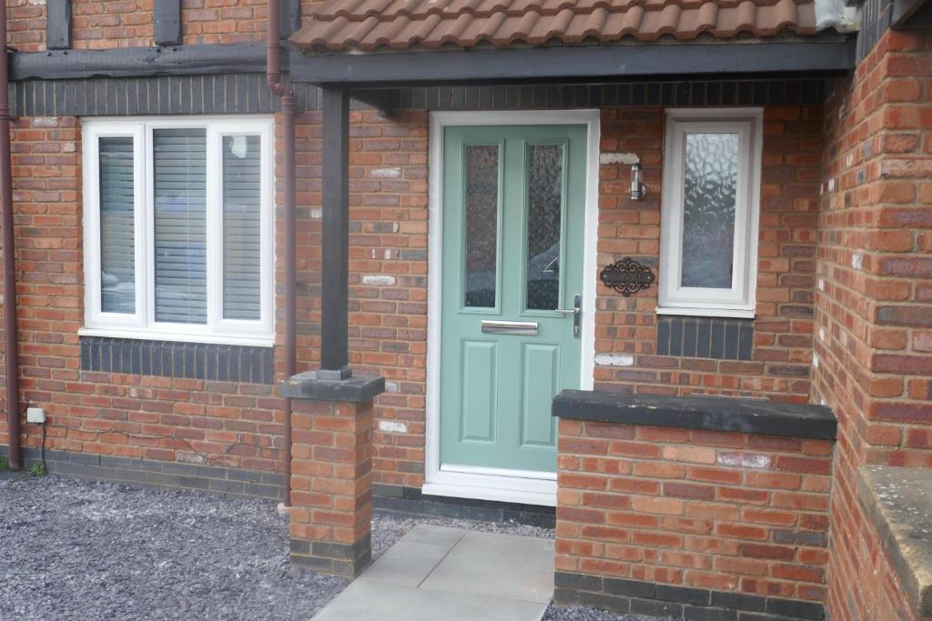 a brick house with a green door and windows at Tranquil 3 bedroom town house with Sky Glass in Thornton