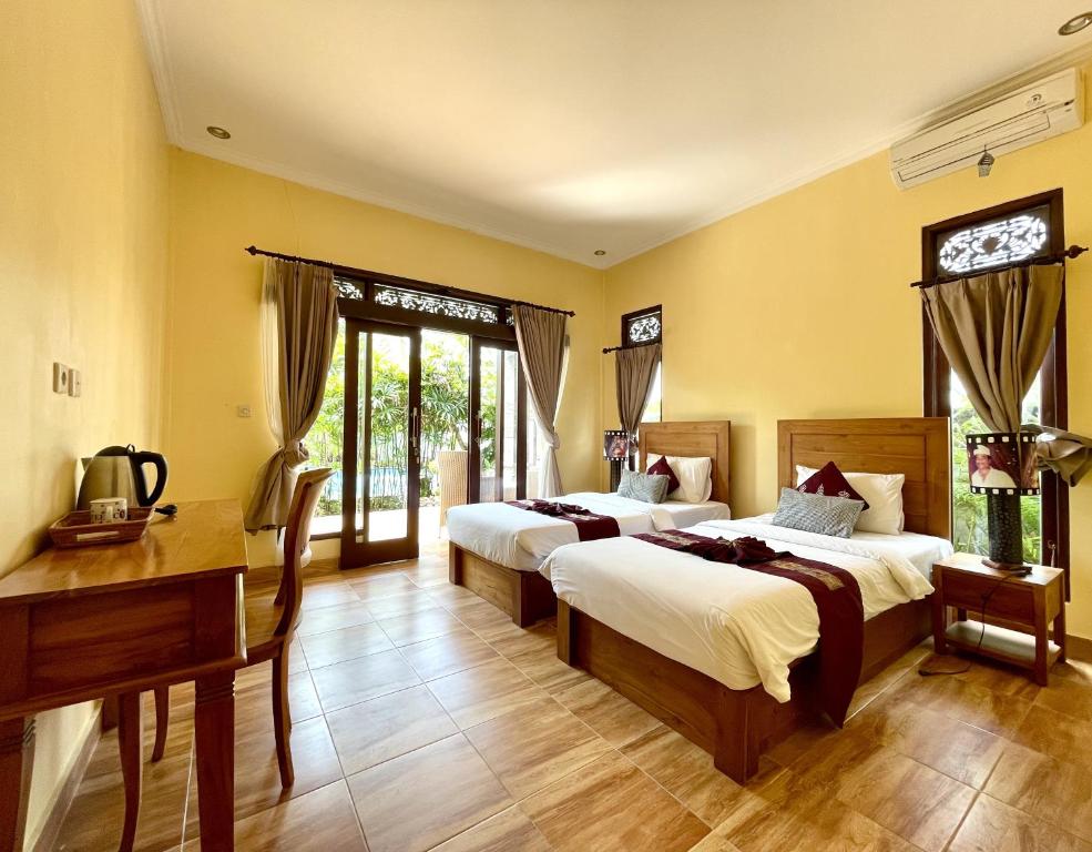 1 dormitorio con 2 camas, escritorio y ventanas en PGS HOME STAY, en Ubud