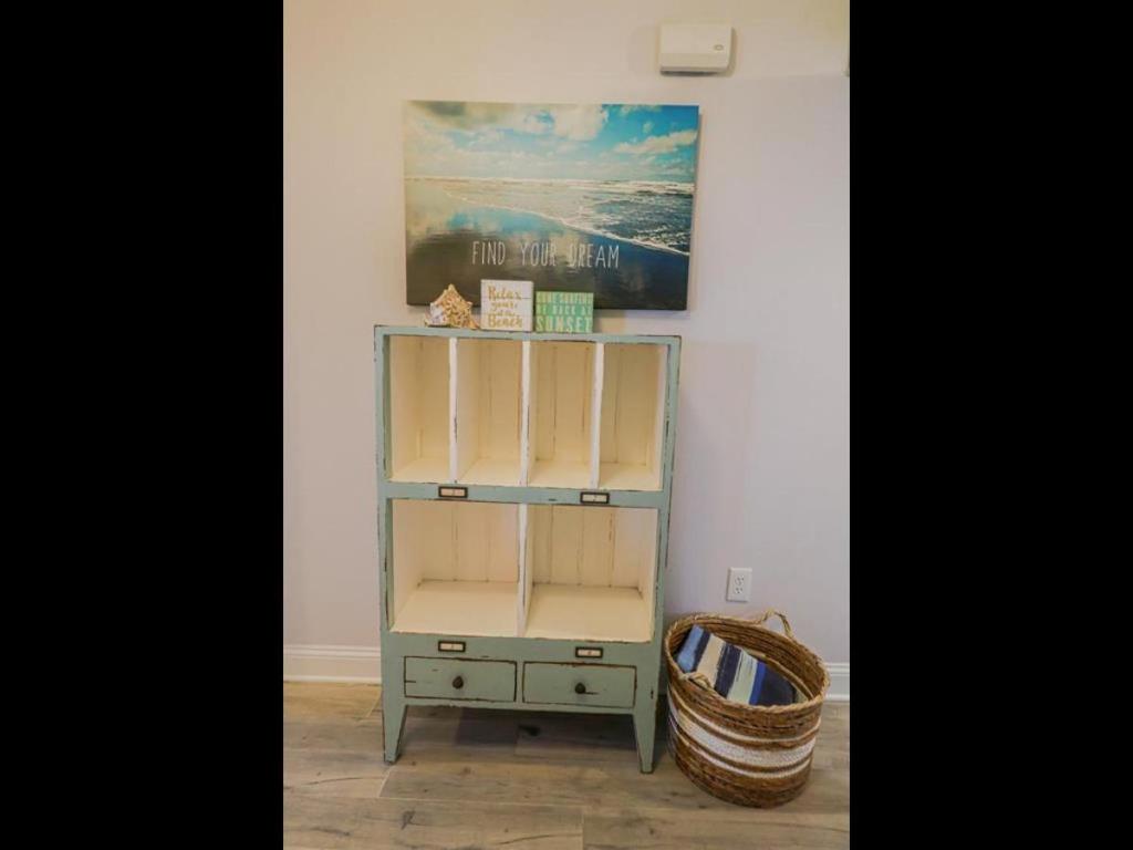 un estante en una habitación con una foto y una cesta en Sand Dollar 3-106, en St. Augustine