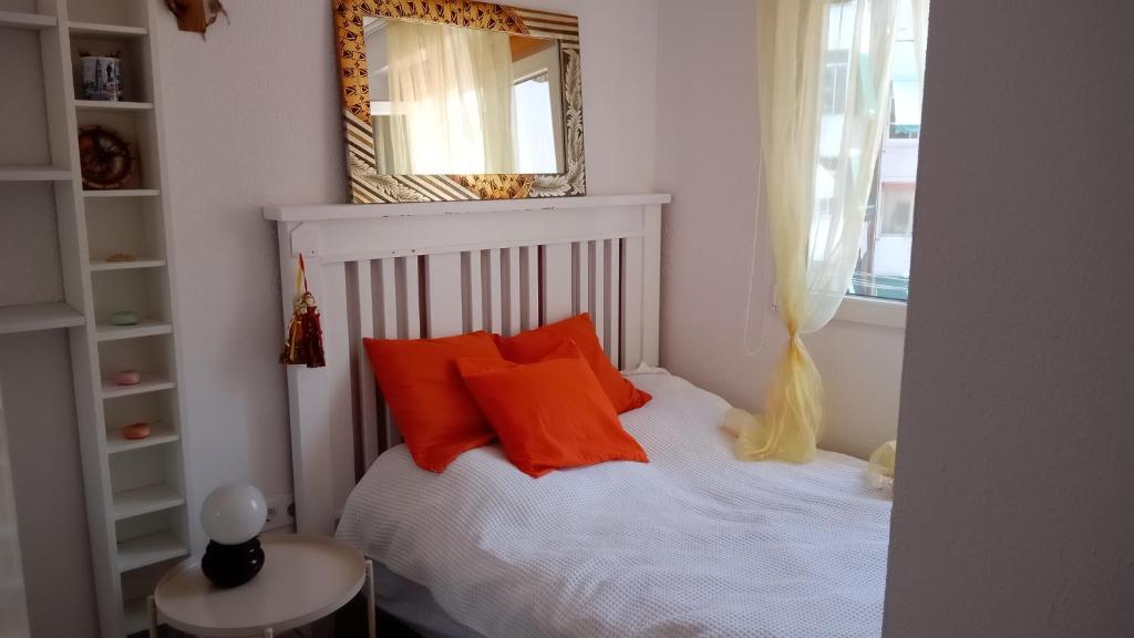 a bedroom with a bed with orange pillows and a mirror at Habitación con baño privado en piso familiar in Alicante