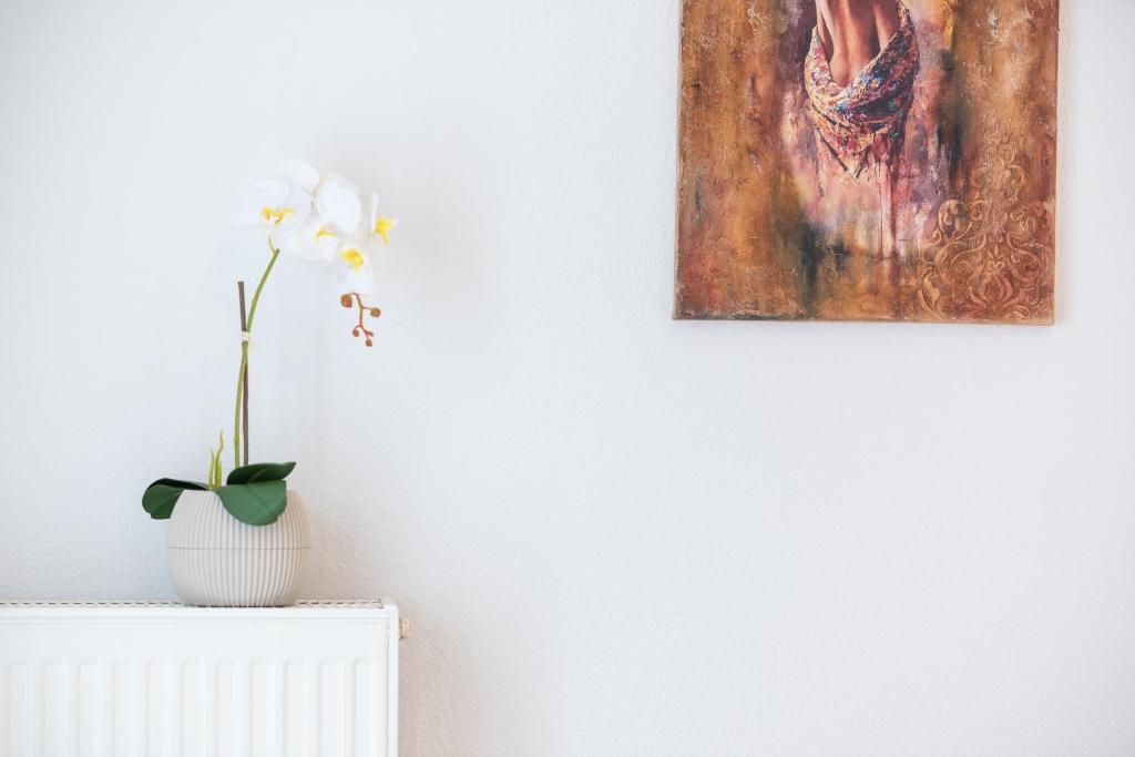 un jarrón blanco con una flor en un radiador junto a una pintura en Porto Ofrynio Central Deluxe Golden Apartment, en Ofrinion