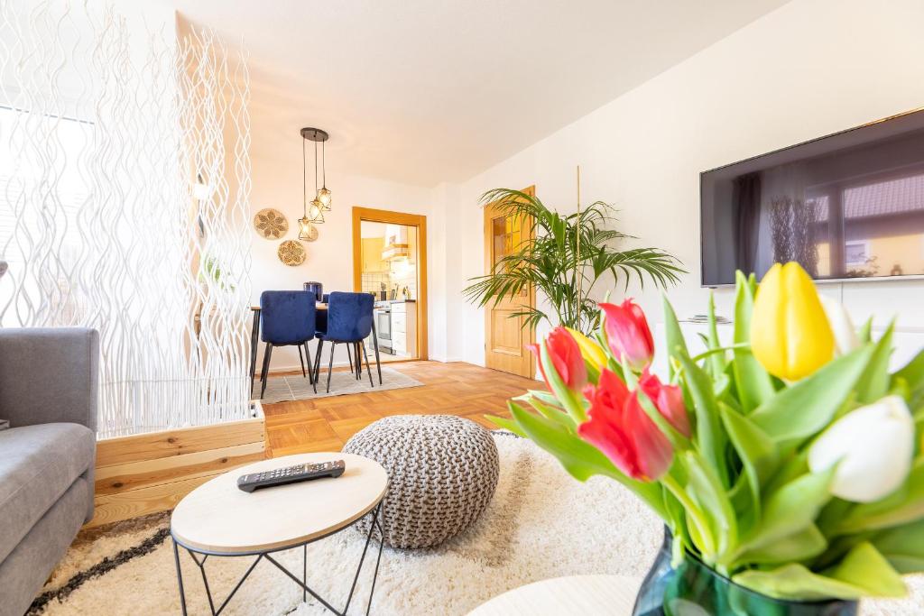 a living room with a couch and a table with flowers at Ferienhaus mit 2 Wohnungen - ideal für Familien & Gruppen in Burgkunstadt