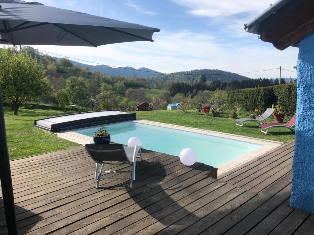 una piscina con una sombrilla en una terraza en La maison bleue, en Altenbach