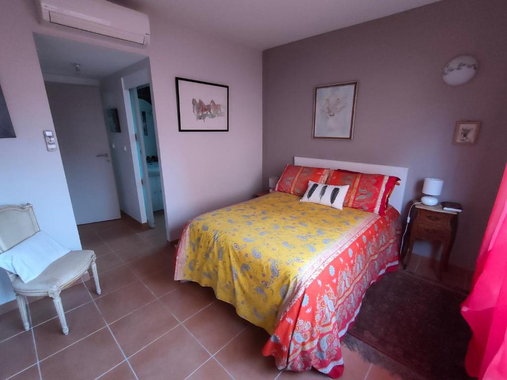 um quarto com uma cama e uma cadeira branca em Chez Régine em Agde