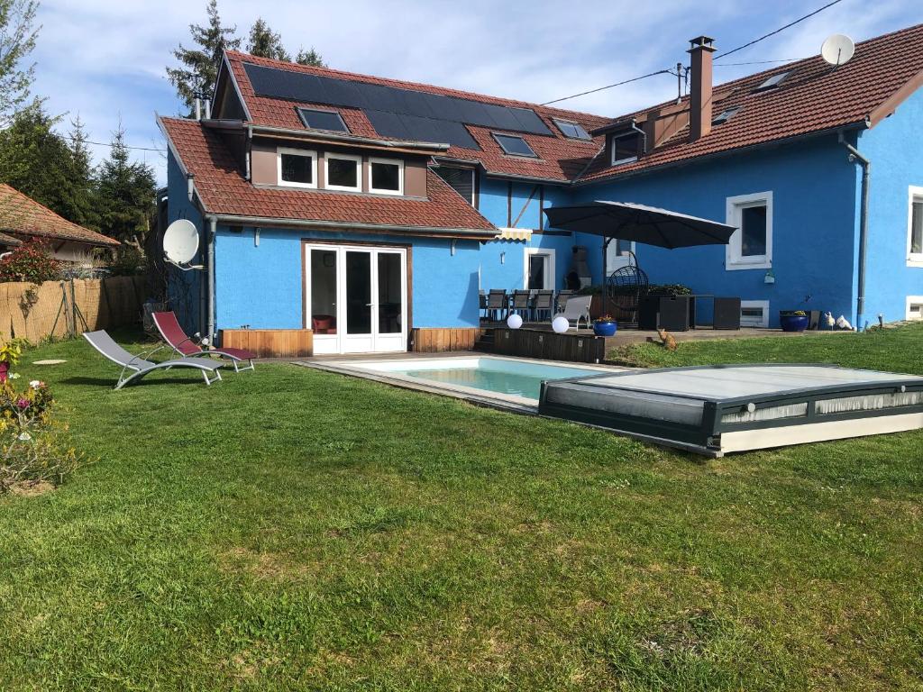 una casa azul con piscina en un patio en La maison bleue, en Altenbach