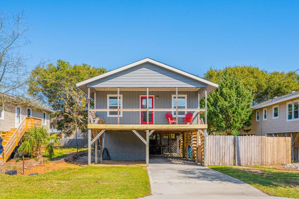 a house with a wrap around porch with red chairs at Offshore Winds - KDH112 in Kill Devil Hills