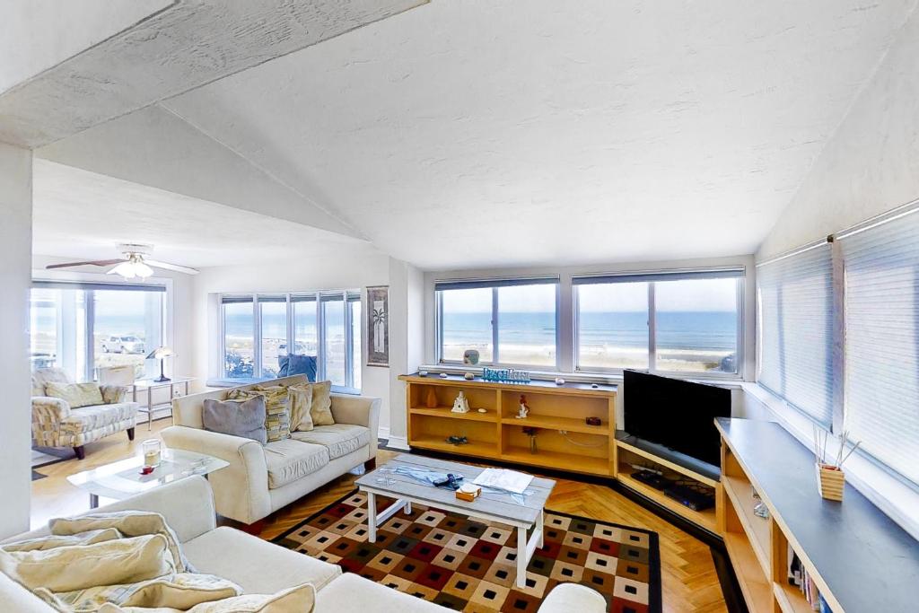 uma sala de estar com mobiliário branco e janelas grandes em Beach House 1703 em Flagler Beach