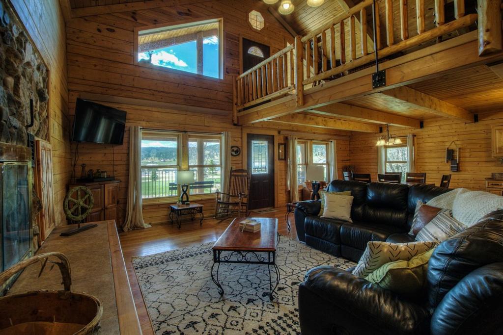 a living room with leather furniture in a log cabin at Waterwheel Retreat in Sturgis