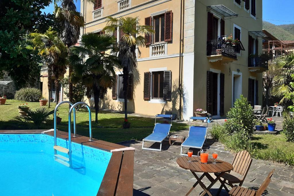 una piscina con sedie e un tavolo accanto a un edificio di Villa Vittorio a Bagni di Lucca