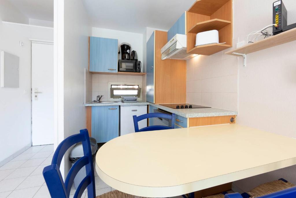 a kitchen with a white table and blue chairs at 1 bedroom apartment in a residence with a swimming pool and a parking spot in Vallauris