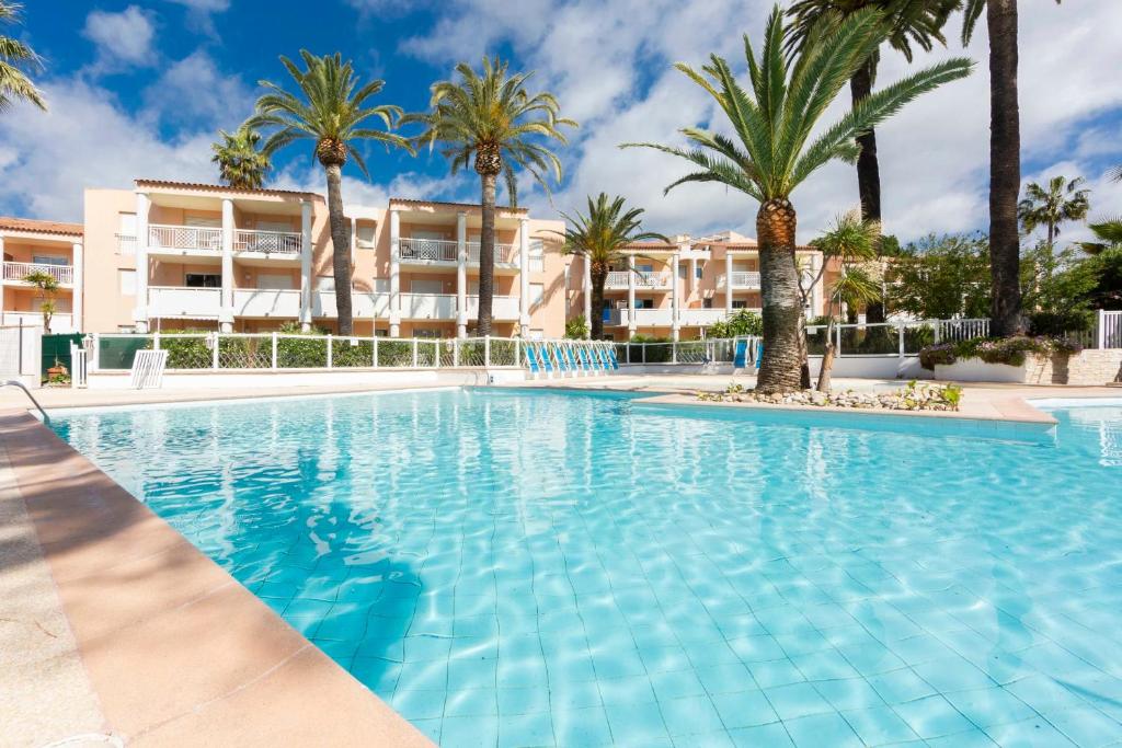 a large swimming pool with palm trees and buildings at 1 bedroom apartment in a residence with a swimming pool and a parking spot in Vallauris