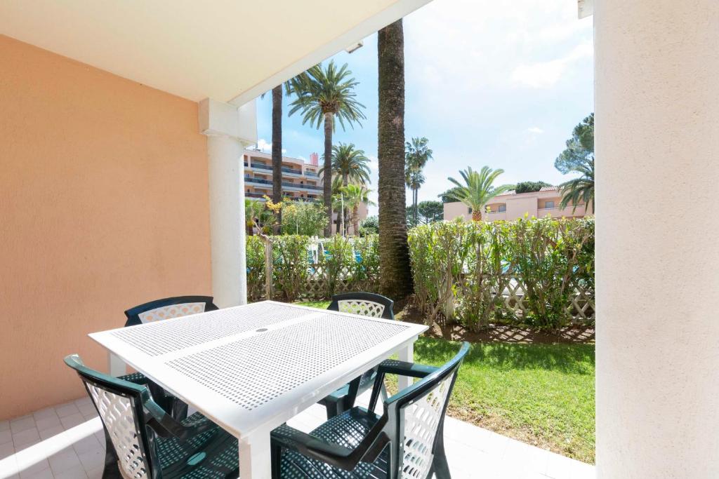 a white table and chairs on a patio with palm trees at 1 bedroom apartment in a residence with a swimming pool and a parking spot in Vallauris