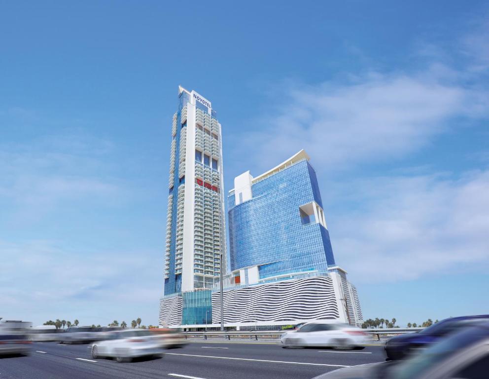 Movenpick Jumeirah Village Triangle في دبي: مبنى طويل وبه سيارات أمام الطريق السريع