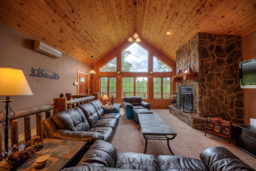 a living room with leather couches and a stone fireplace at Lazy Bear Lodge in Sturgis