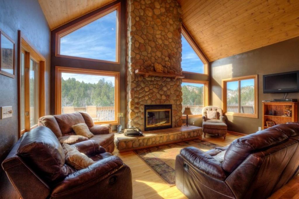 sala de estar con muebles de cuero y chimenea de piedra. en Aces and Eights Lodge en Sturgis