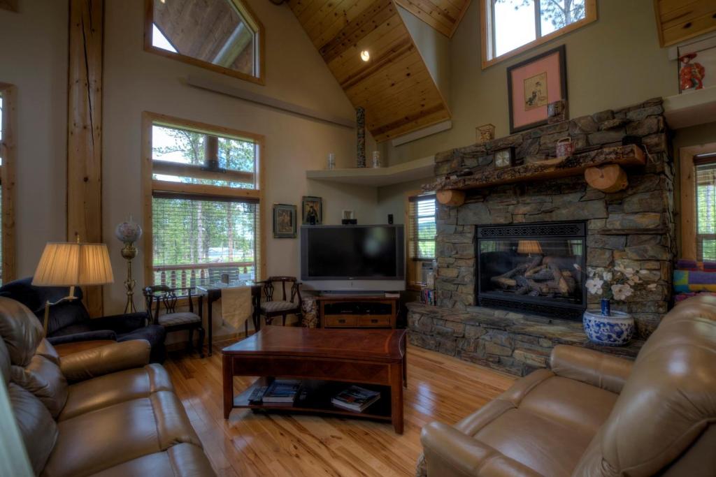 a living room with a stone fireplace and a television at Boulder Ridge Lodge in Lead