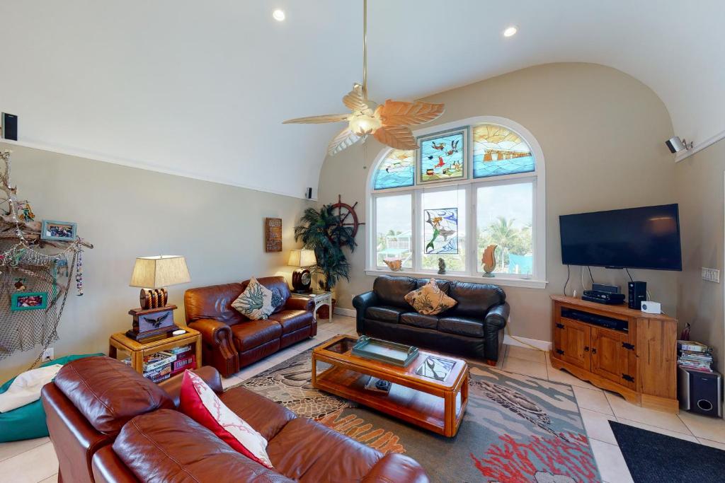 a living room with leather furniture and a flat screen tv at The Mermaid Manor in Cudjoe Key