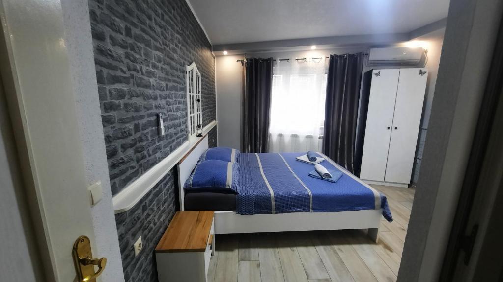 ein Schlafzimmer mit einem blauen Bett und einer Backsteinwand in der Unterkunft APP BENI in Crikvenica