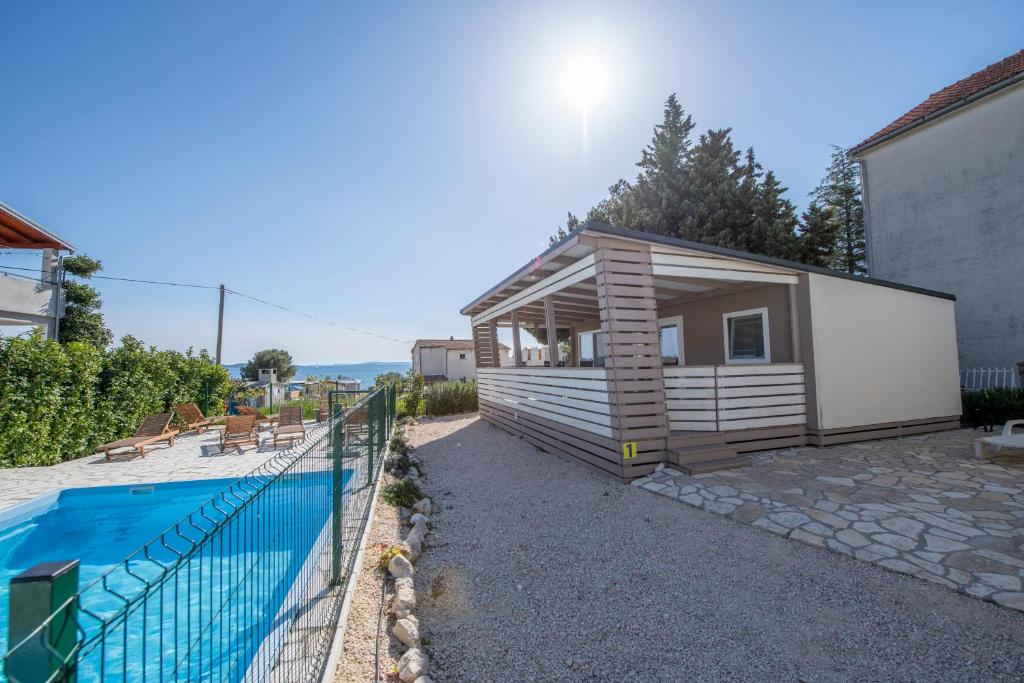 a tiny house next to a swimming pool at Mali Nordsee Camp - DeLuxe Mobilehome in Pakoštane